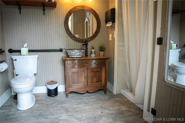 bathroom featuring vanity, toilet, baseboards, and a shower stall