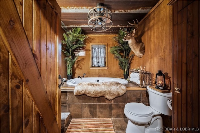 full bathroom featuring toilet, a garden tub, and wooden walls