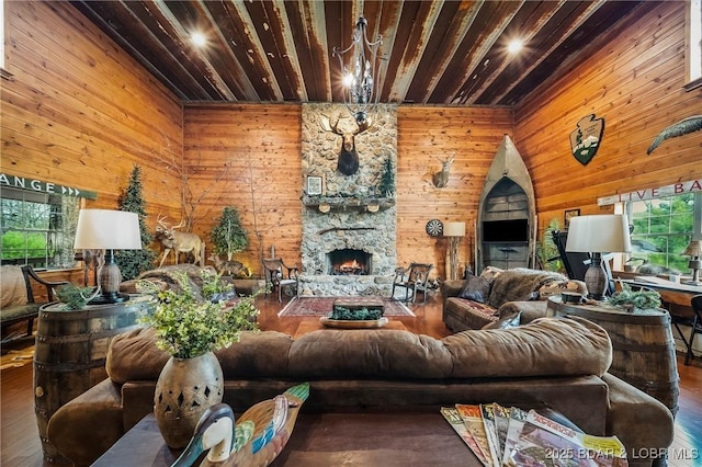 living area featuring wooden ceiling, wood walls, wood finished floors, and a stone fireplace