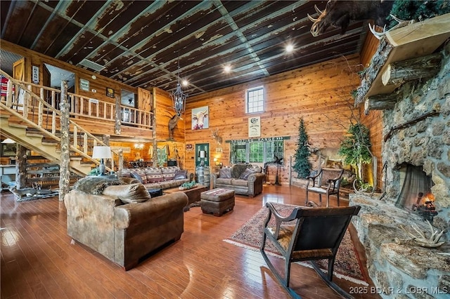living room featuring stairs, wooden walls, hardwood / wood-style floors, and a high ceiling