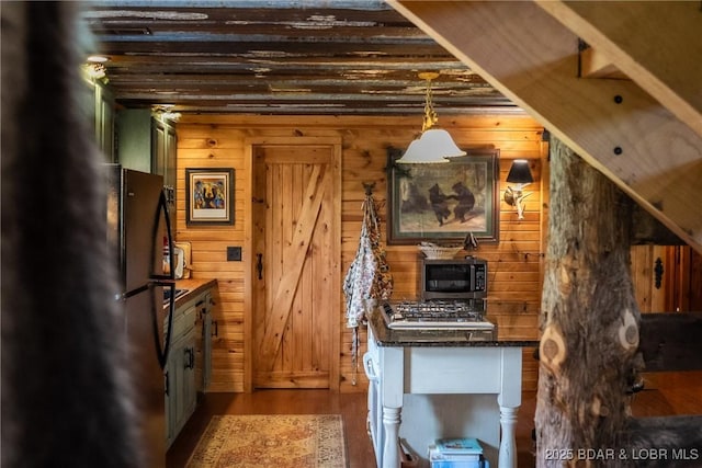 kitchen featuring wooden walls, wood finished floors, and appliances with stainless steel finishes
