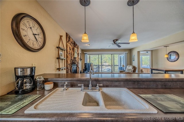 kitchen featuring a sink, dark countertops, hanging light fixtures, and a ceiling fan