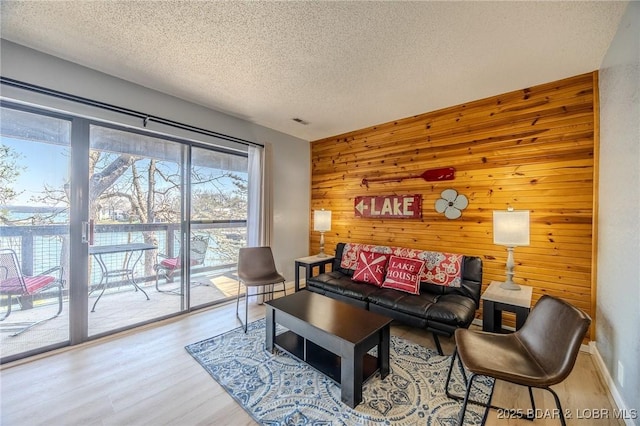 256 Lone Oak Pt Unit 15, Sunrise Beach, MO 65079 - living room with visible vents, wood walls, a textured ceiling, and wood finished floors