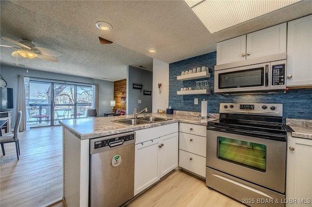 256 Lone Oak Pt Unit 15, Sunrise Beach, MO 65079 - kitchen featuring white cabinets, a sink, stainless steel appliances, a peninsula, and light wood-type flooring