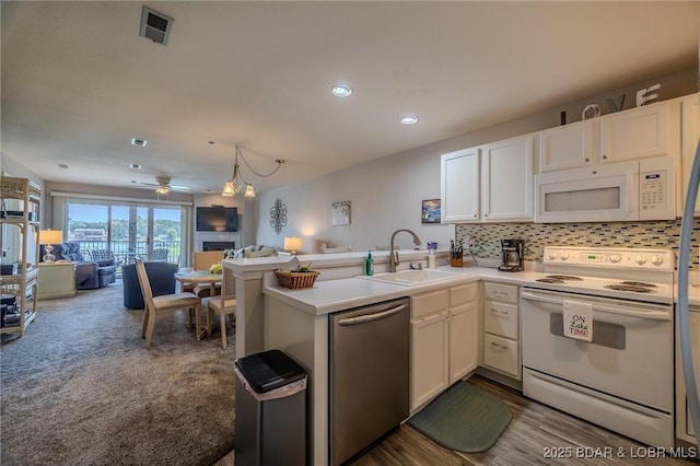 kitchen featuring visible vents, white appliances, open floor plan, white cabinets, and a sink