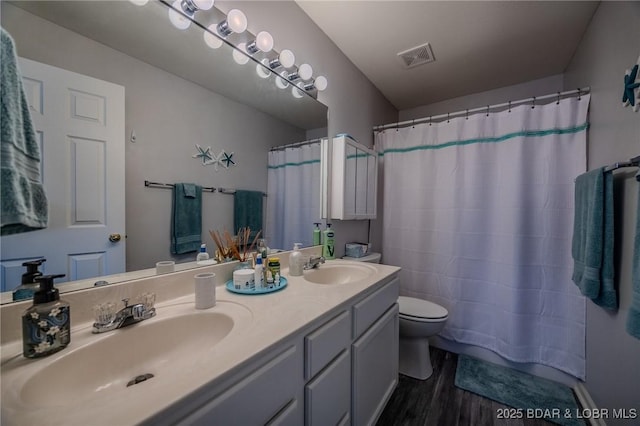 full bathroom with a sink, toilet, wood finished floors, and visible vents
