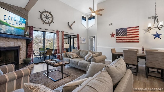 living area featuring high vaulted ceiling, visible vents, wood finished floors, and ceiling fan with notable chandelier