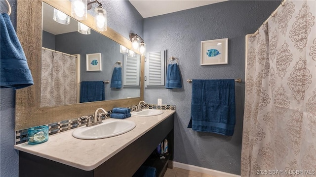 full bath featuring a sink, tile patterned floors, a textured wall, and double vanity
