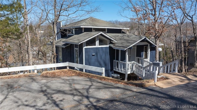 rustic home with a porch, a chimney, and a shingled roof