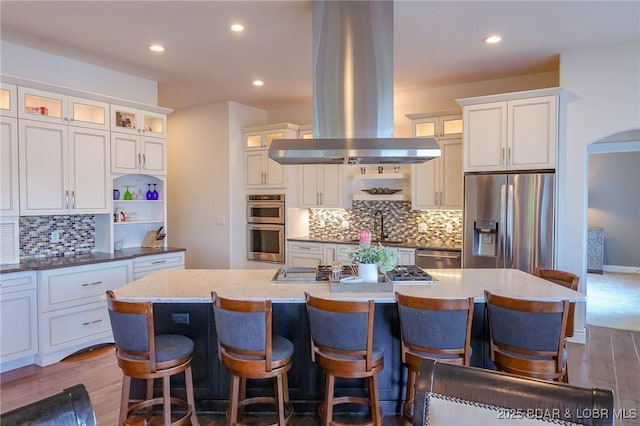 kitchen with dark wood-style flooring, appliances with stainless steel finishes, island range hood, and recessed lighting