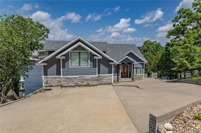 craftsman-style house with roof with shingles and stone siding