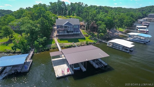 birds eye view of property featuring a water view and a wooded view