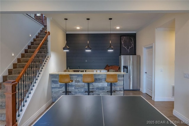 kitchen featuring visible vents, ornamental molding, wood finished floors, baseboards, and stainless steel fridge with ice dispenser