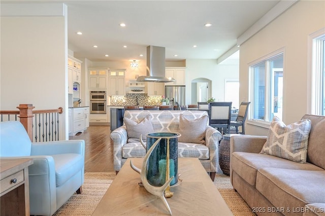 living area featuring arched walkways, recessed lighting, and light wood-style flooring