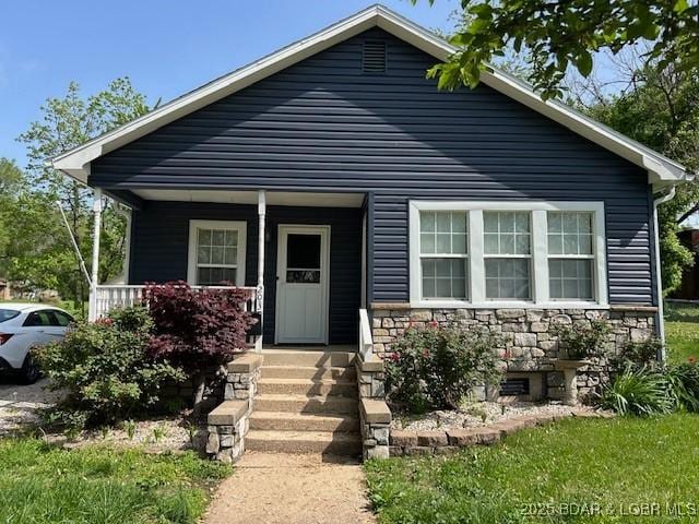 bungalow-style home featuring a porch and stone siding