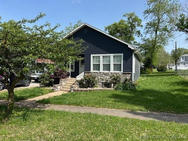 bungalow with a front yard and stone siding
