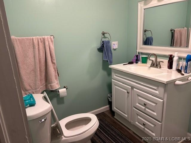 bathroom with vanity, baseboards, toilet, and wood finished floors