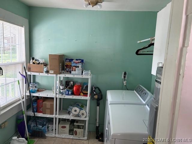 washroom with washing machine and clothes dryer, laundry area, a healthy amount of sunlight, and tile patterned floors