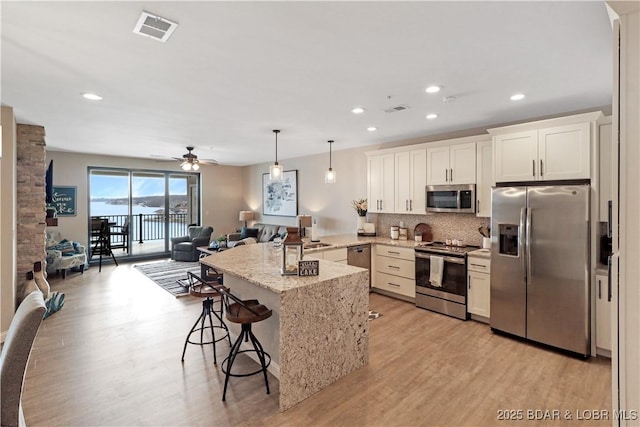 166 Captiva Dr Unit 5B, Sunrise Beach, MO 65079 - kitchen with visible vents, appliances with stainless steel finishes, a peninsula, open floor plan, and light wood-style floors