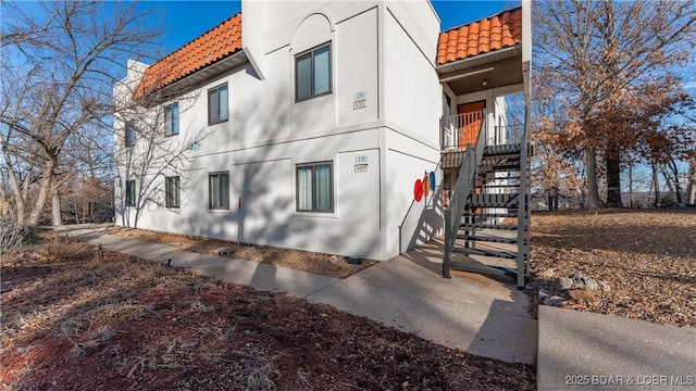 67 Ventura Dr Unit 427, Lake Ozark, MO 65049 - view of home's exterior featuring a tiled roof, stairway, and stucco siding