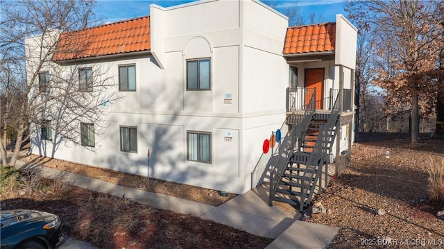 67 Ventura Dr Unit 427, Lake Ozark, MO 65049 - view of property exterior featuring a tiled roof, stucco siding, and stairway