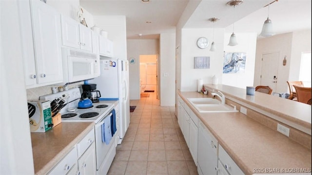 kitchen with pendant lighting, white appliances, white cabinetry, a sink, and light tile patterned floors
