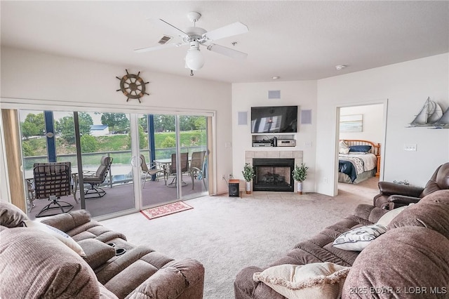 living area with ceiling fan, light colored carpet, and a tiled fireplace