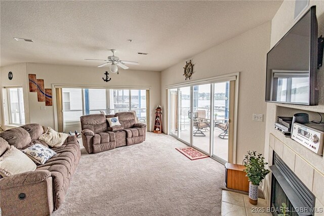 living room featuring a ceiling fan, a textured ceiling, visible vents, and light carpet