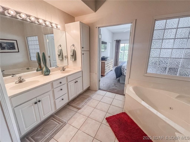 ensuite bathroom with double vanity, a sink, a bath, and tile patterned floors