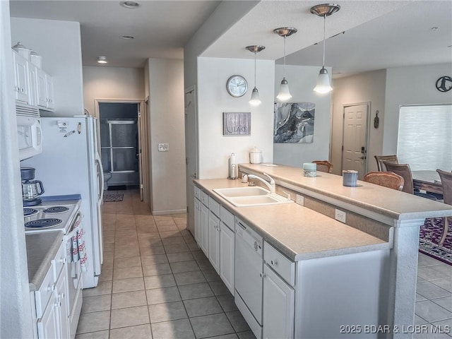 kitchen featuring a peninsula, white appliances, white cabinetry, a sink, and light tile patterned floors