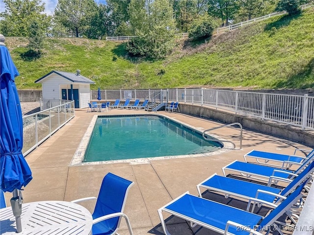 pool featuring fence, an outbuilding, and a patio area