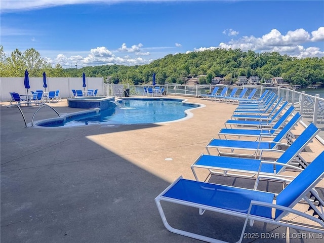 view of swimming pool with fence, a patio, and a pool with connected hot tub
