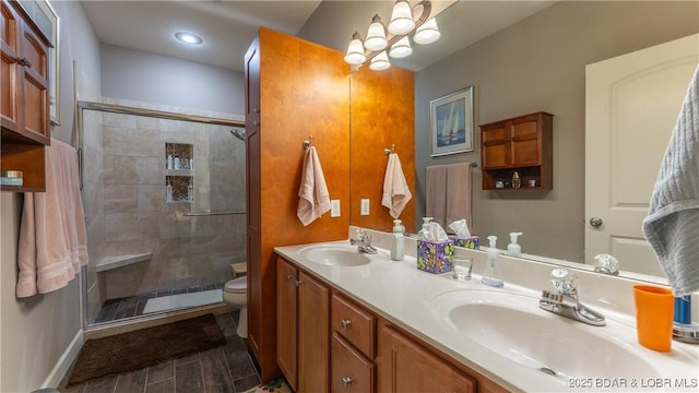 full bathroom with double vanity, a sink, a stall shower, and toilet