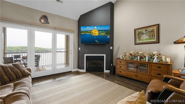 living room featuring a fireplace, high vaulted ceiling, baseboards, wood finished floors, and visible vents