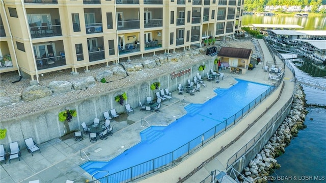 pool with a water view, a patio area, and fence