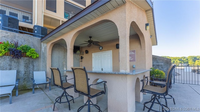 view of patio featuring fence, outdoor dry bar, and a ceiling fan