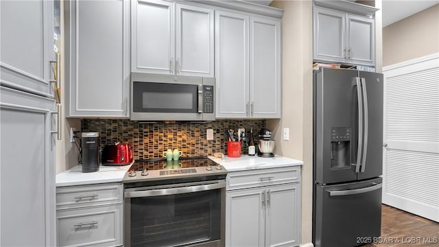 kitchen featuring light countertops, appliances with stainless steel finishes, tasteful backsplash, and wood finished floors