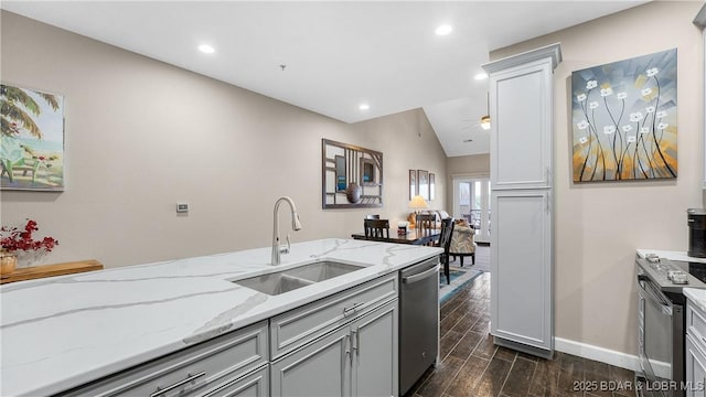 kitchen with a sink, baseboards, light stone counters, dark wood-style floors, and stainless steel appliances