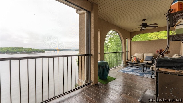 balcony featuring a water view, ceiling fan, and outdoor lounge area