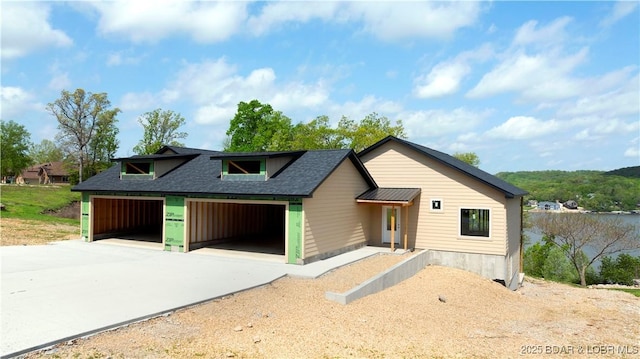 view of front facade with roof with shingles and concrete driveway