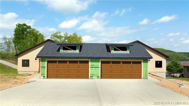 view of front of property featuring a garage, a shingled roof, and concrete driveway