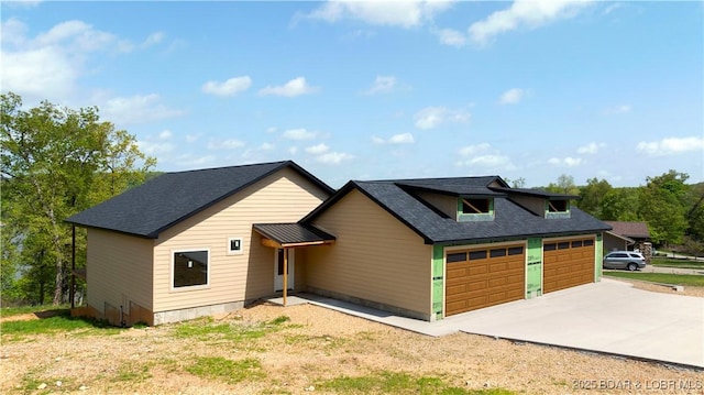 view of front of home with roof with shingles, an attached garage, and driveway