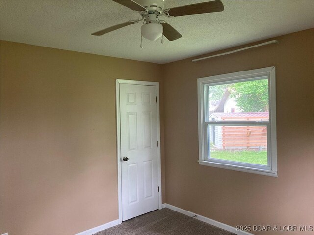412 Jefferson St, Versailles, MO 65084 - empty room featuring baseboards, dark carpet, a textured ceiling, and a ceiling fan