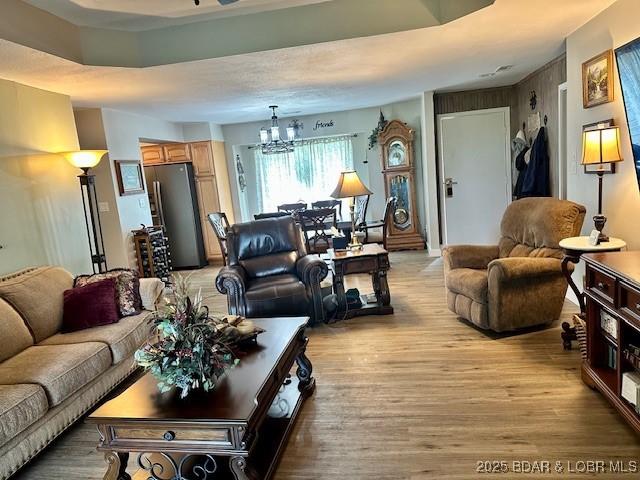 living area with light wood-style floors and a notable chandelier