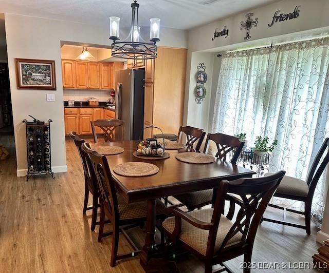 dining room with baseboards, a notable chandelier, and light wood-style flooring