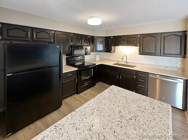 1117 Passover Rd Unit K-8, Osage Beach, MO 65065 - kitchen with black appliances, a textured ceiling, light wood-style floors, tasteful backsplash, and light stone counters
