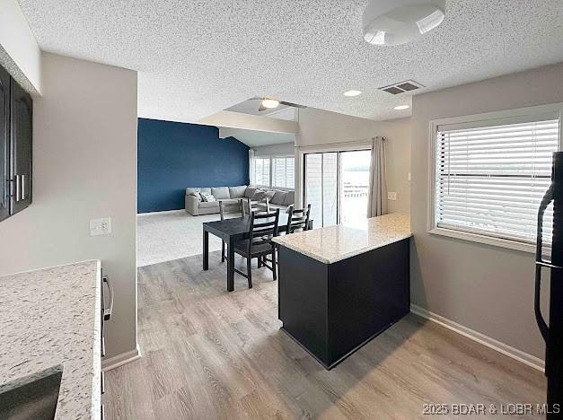 1117 Passover Rd Unit K-8, Osage Beach, MO 65065 - kitchen with light wood-style flooring, light countertops, a textured ceiling, a peninsula, and freestanding refrigerator