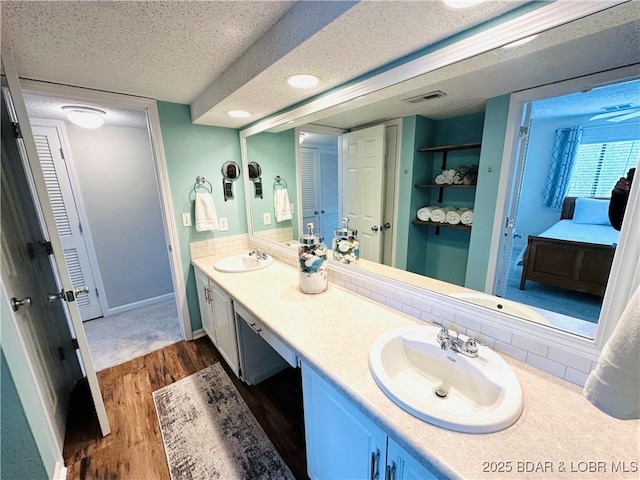1117 Passover Rd Unit K-8, Osage Beach, MO 65065 - full bathroom featuring wood finished floors, double vanity, a textured ceiling, ensuite bath, and a closet