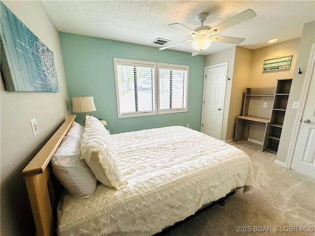 carpeted bedroom featuring visible vents, a ceiling fan, and a textured ceiling