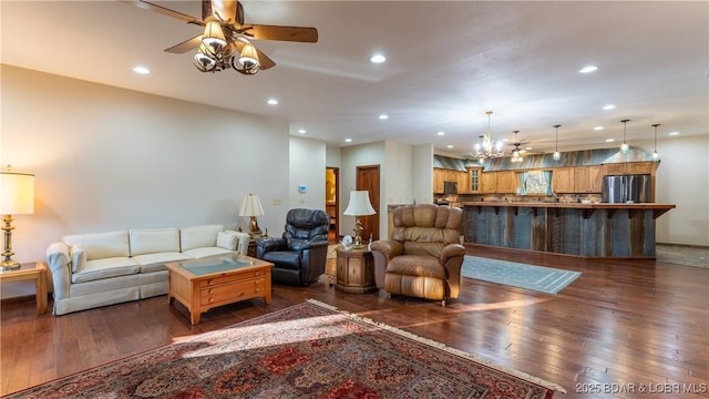 living room featuring recessed lighting, baseboards, ceiling fan with notable chandelier, and dark wood-style floors